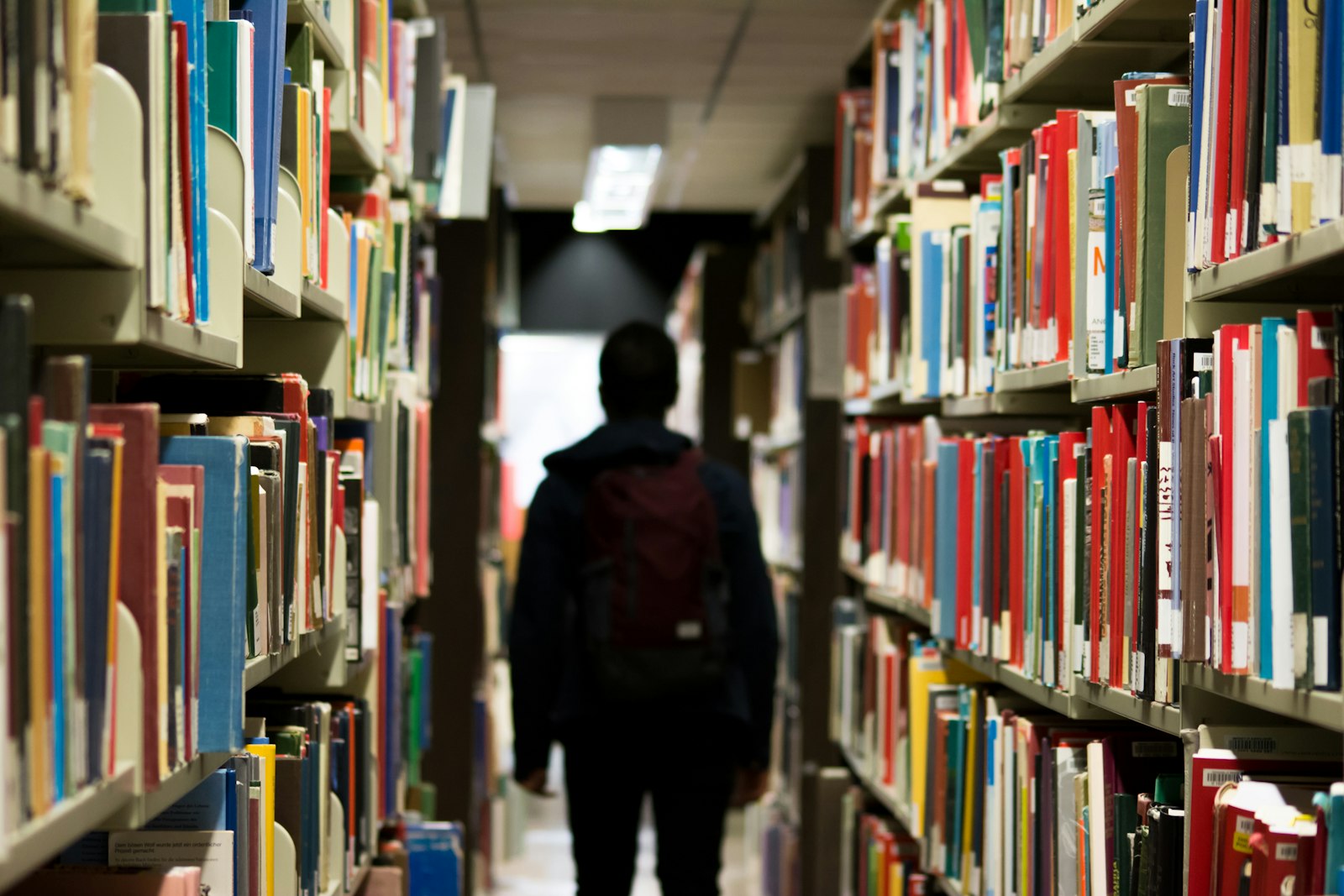 A student walking through library stacks